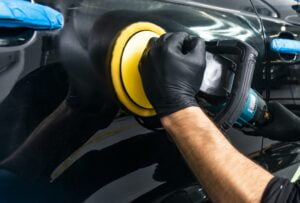 Buffing and polishing car. Car detailing. Man holds a polisher in the hand and polishes the car